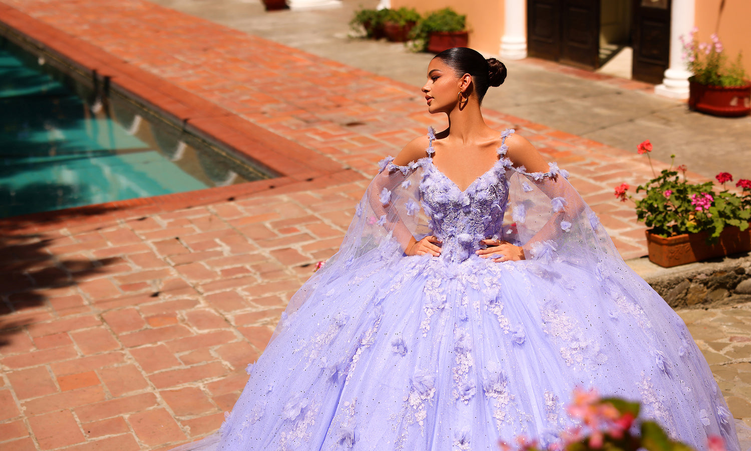 Model by a pool in a lilac ball gown with cape sleeves and three-dimensional flowers
