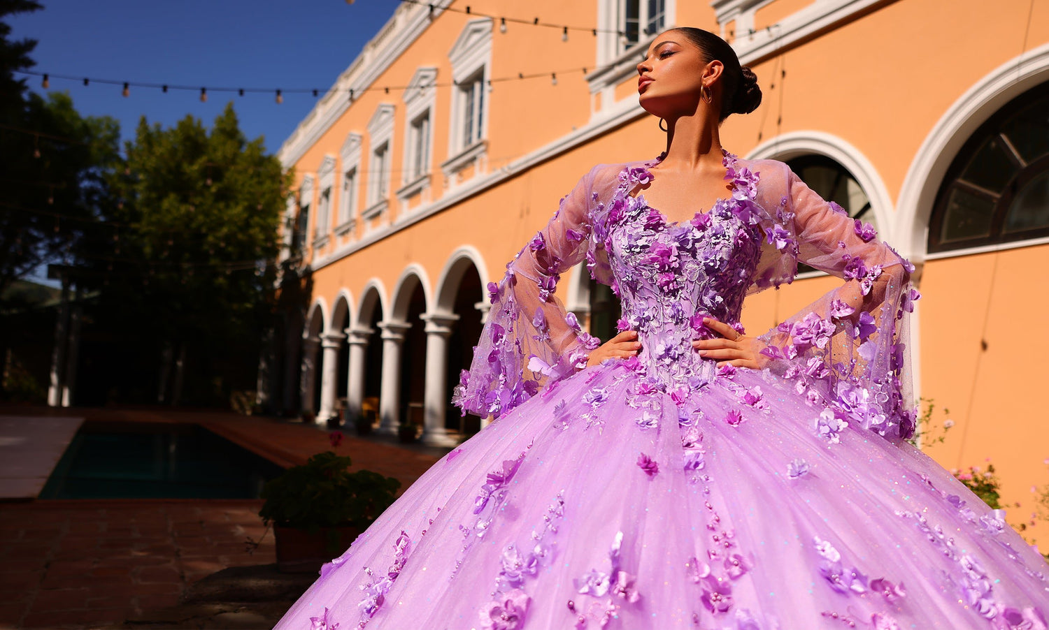Model in a purple ball gown with sheer floral sleeves and three-dimensional blossoms