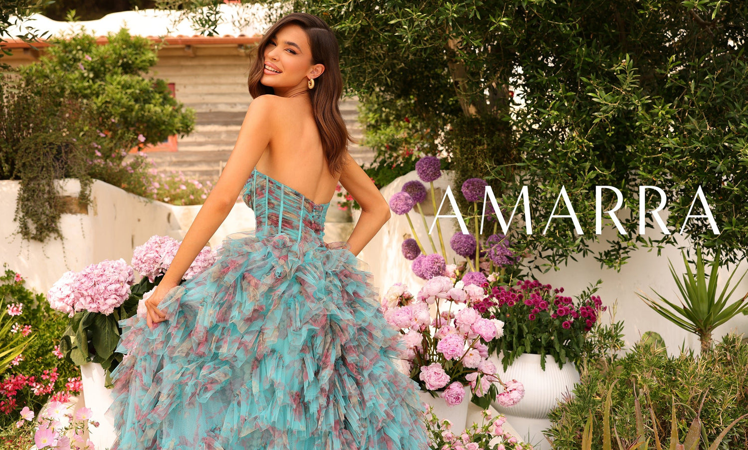 Model facing away in strapless teal ruffled tulle gown with corset back, garden of pink blooms