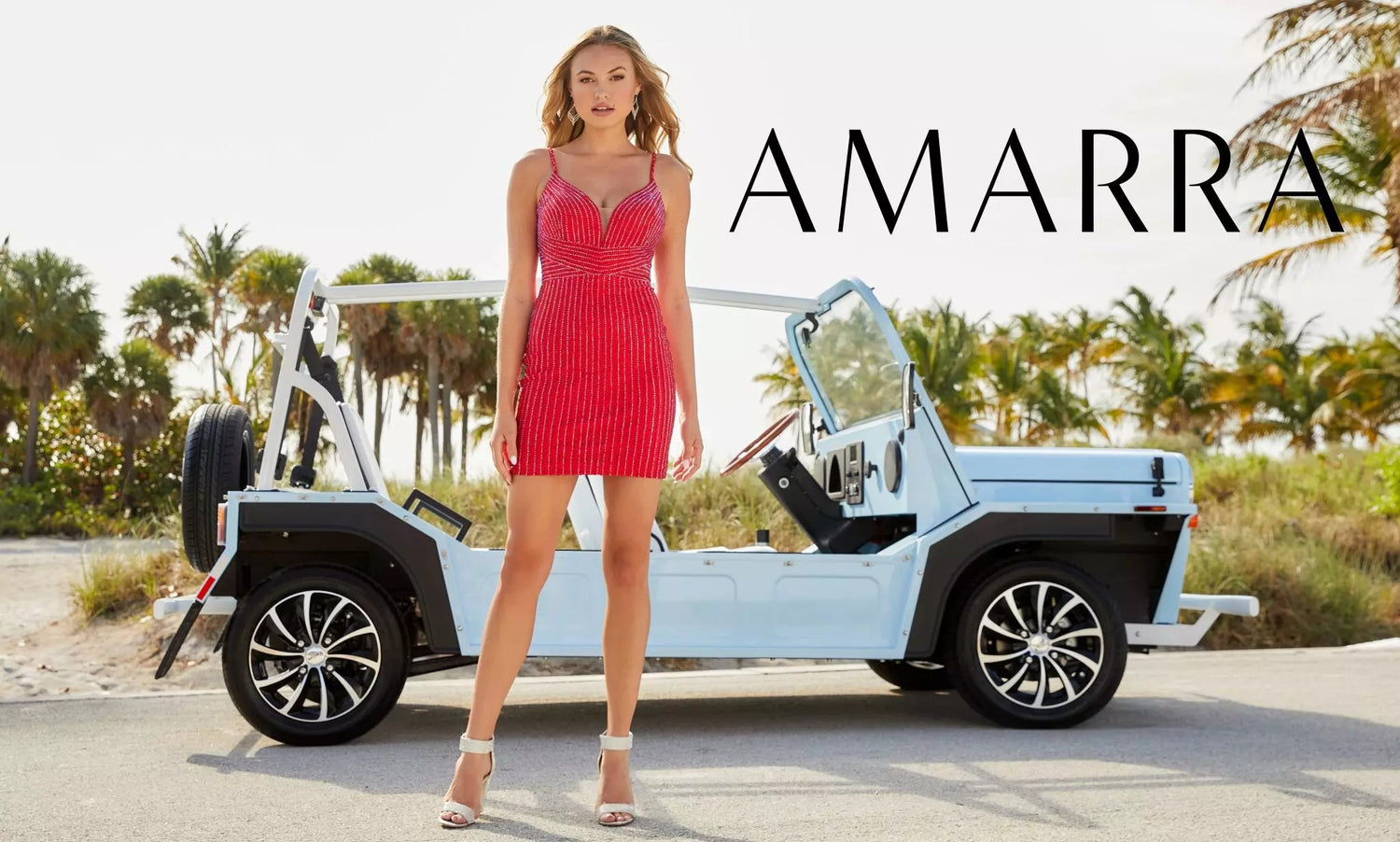 Model in a red beaded mini dress standing in front of a pale blue open-top jeep