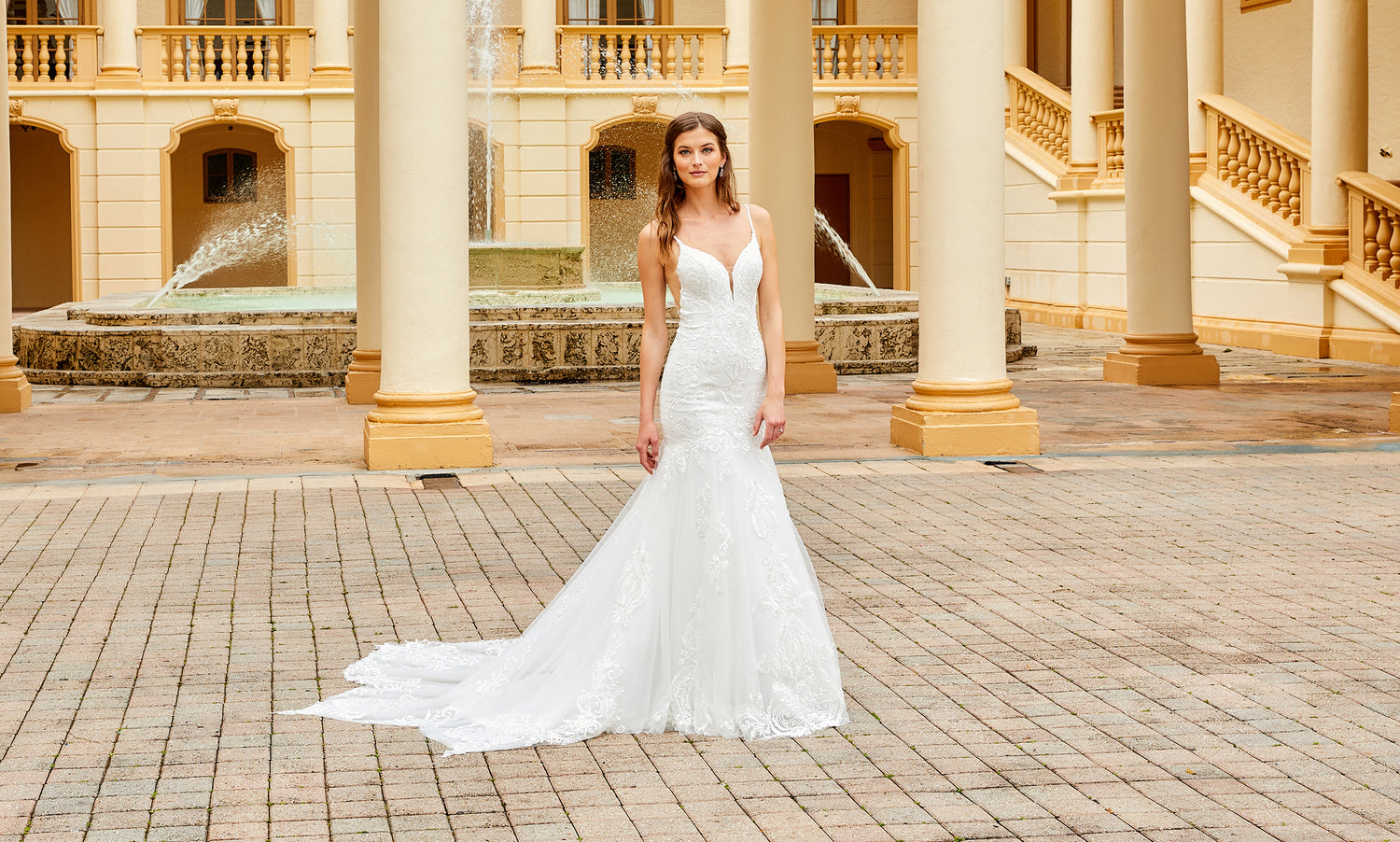 Brunette bride with long straight hair in a white lace mermaid gown with a sweeping train