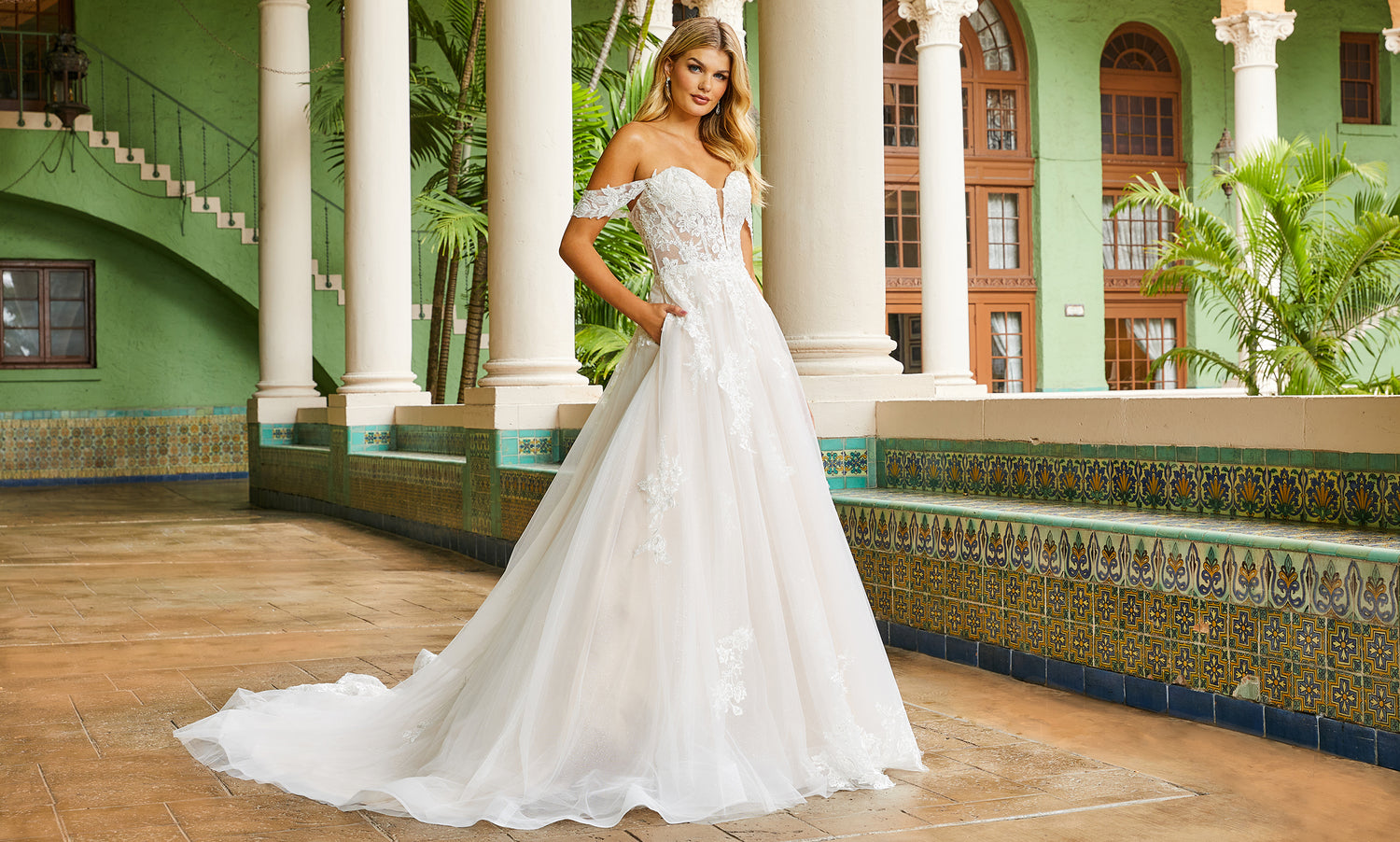 Bride in an off-shoulder lace and tulle ball gown with pockets in a tiled green arcade