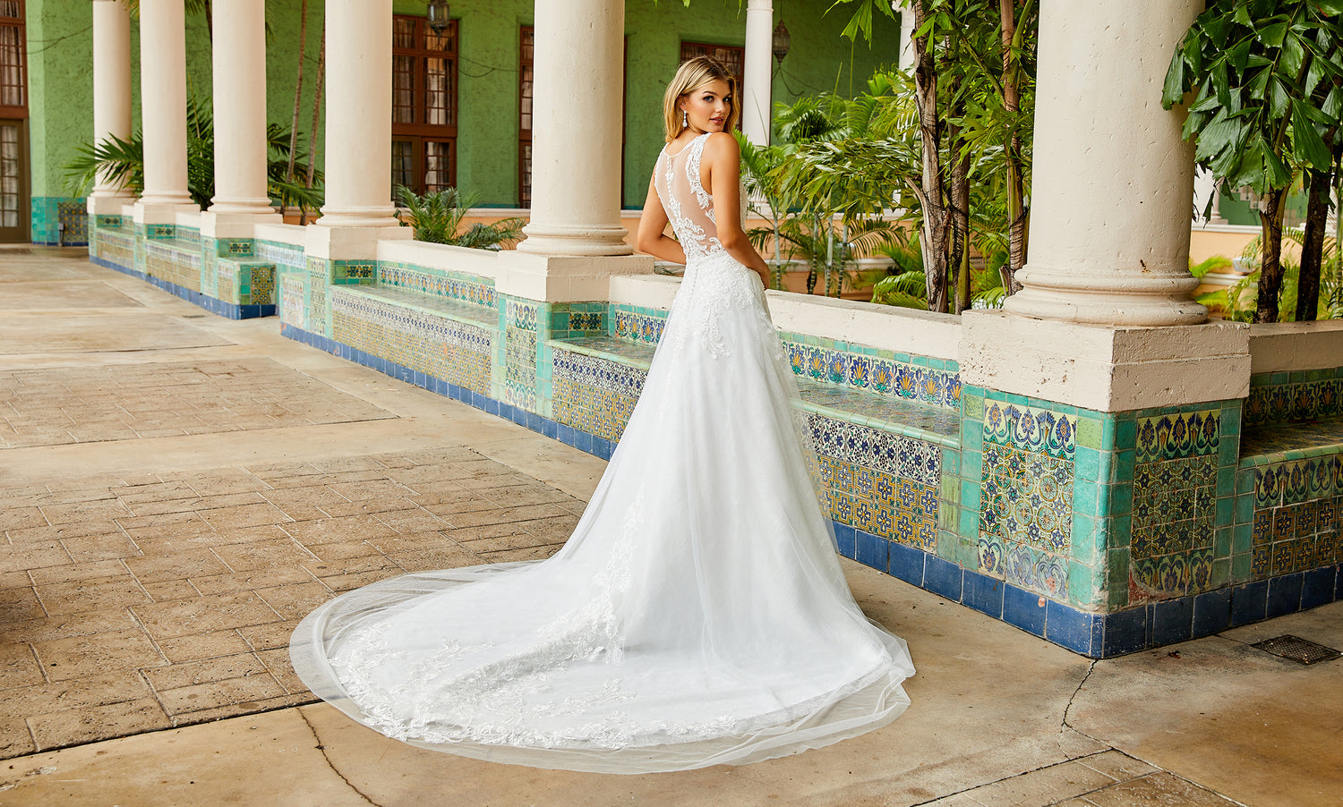 Bride photographed from behind in a white lace A-line gown with an extra-long cathedral train