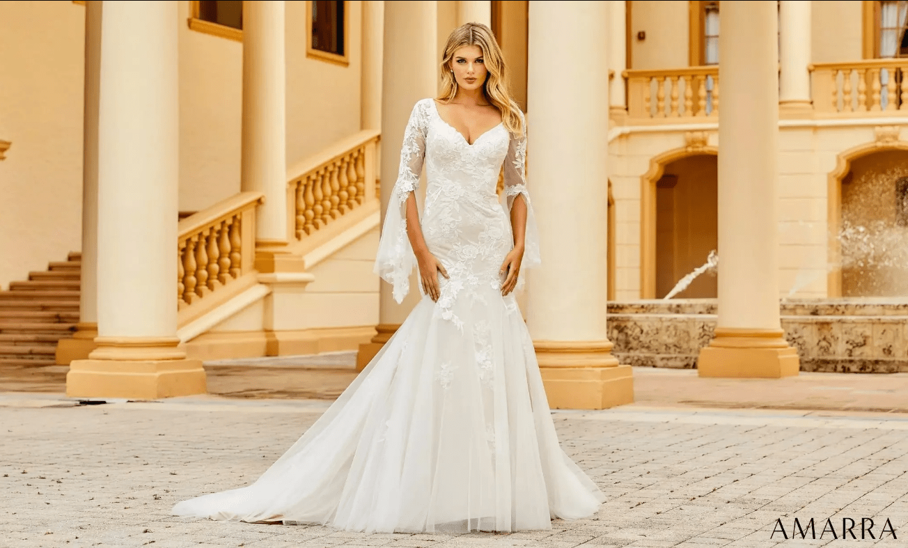 Bride in an ivory lace fit-and-flare gown with sheer bell sleeves outside a yellow columned palazzo