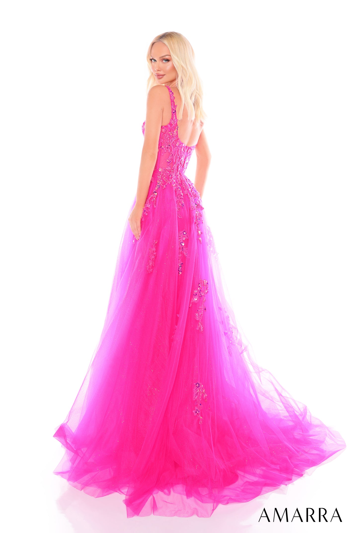 A blonde model wears a hot pink, floor-length tulle gown with beaded embellishments and a flowing train.