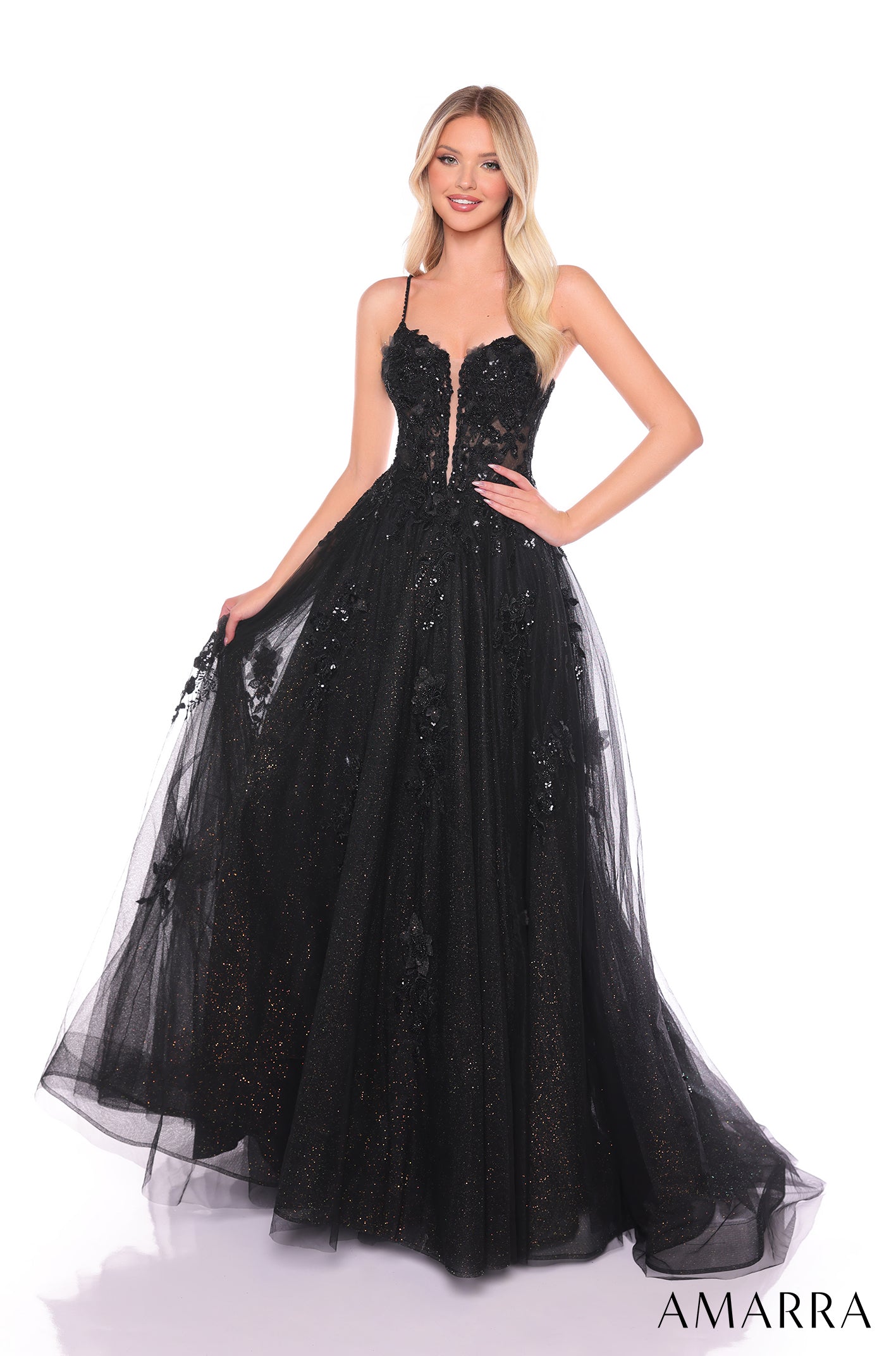 A blonde model wears a black sparkling tulle ball gown with a sweetheart neckline and spaghetti straps.