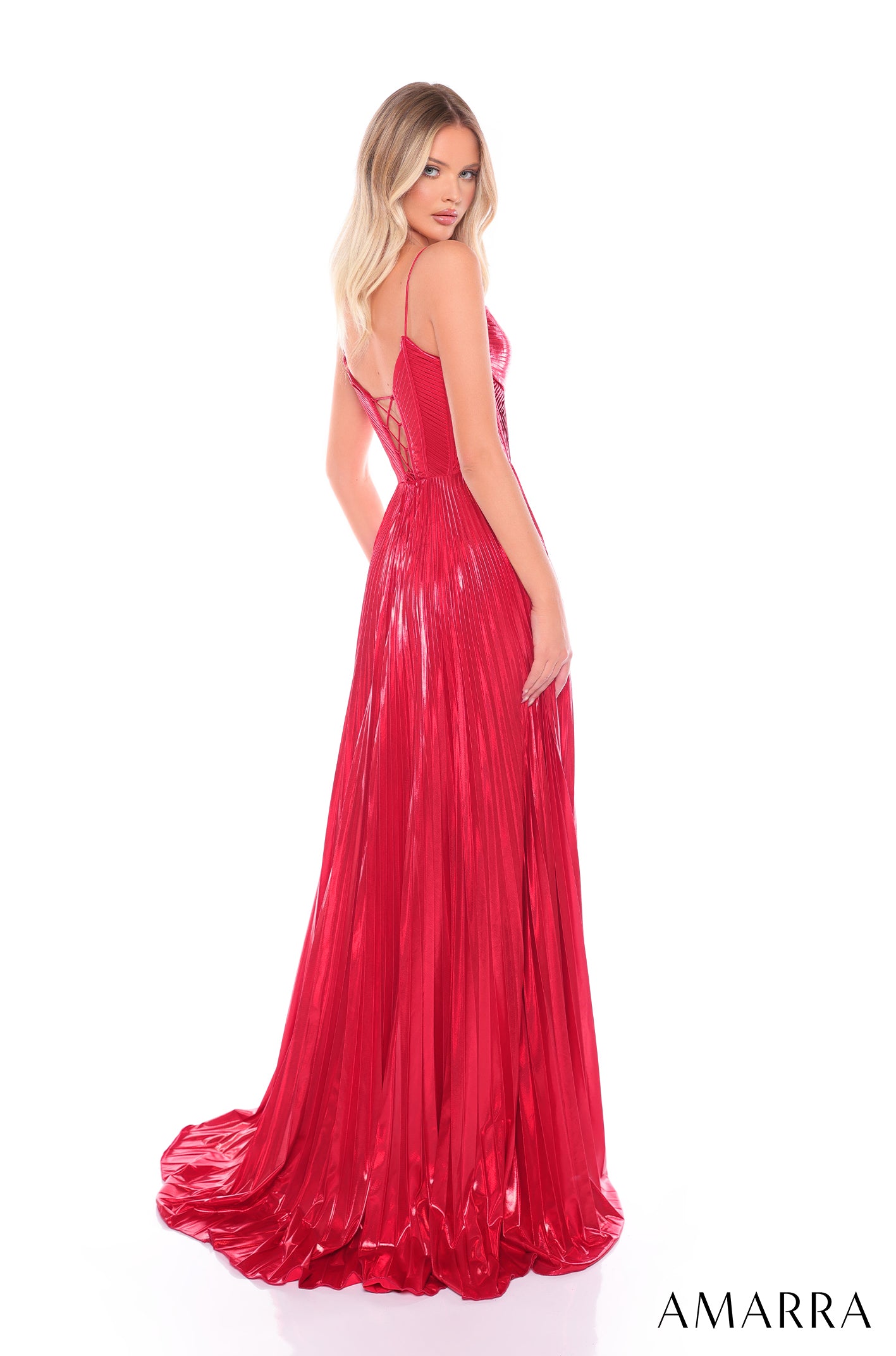 A blonde woman wears a vibrant red pleated gown with a corset-style bodice and flowing train.