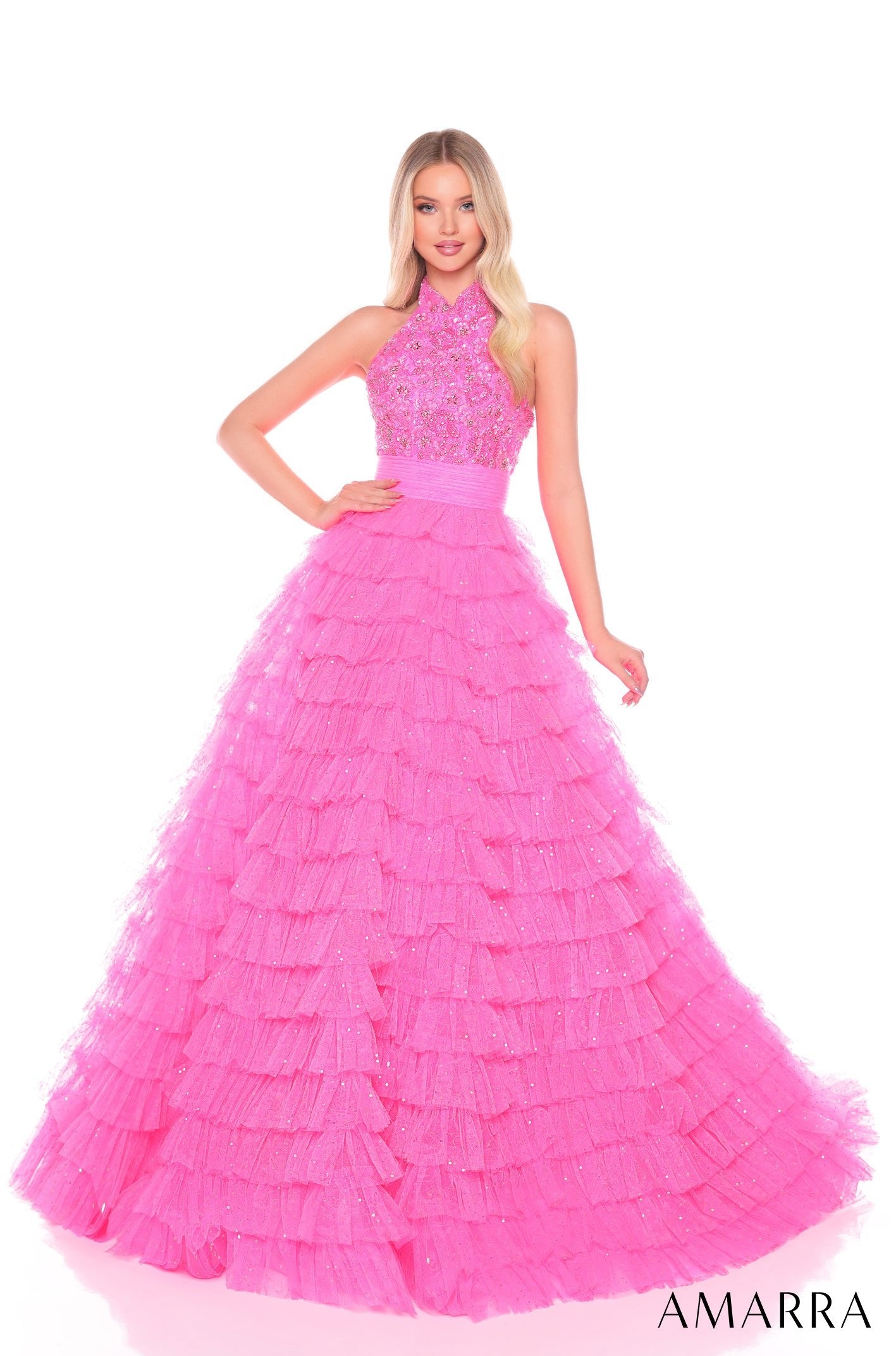 A woman wears a tiered, ruffled Hot Pink ball gown with a beaded halter top by Amarra.