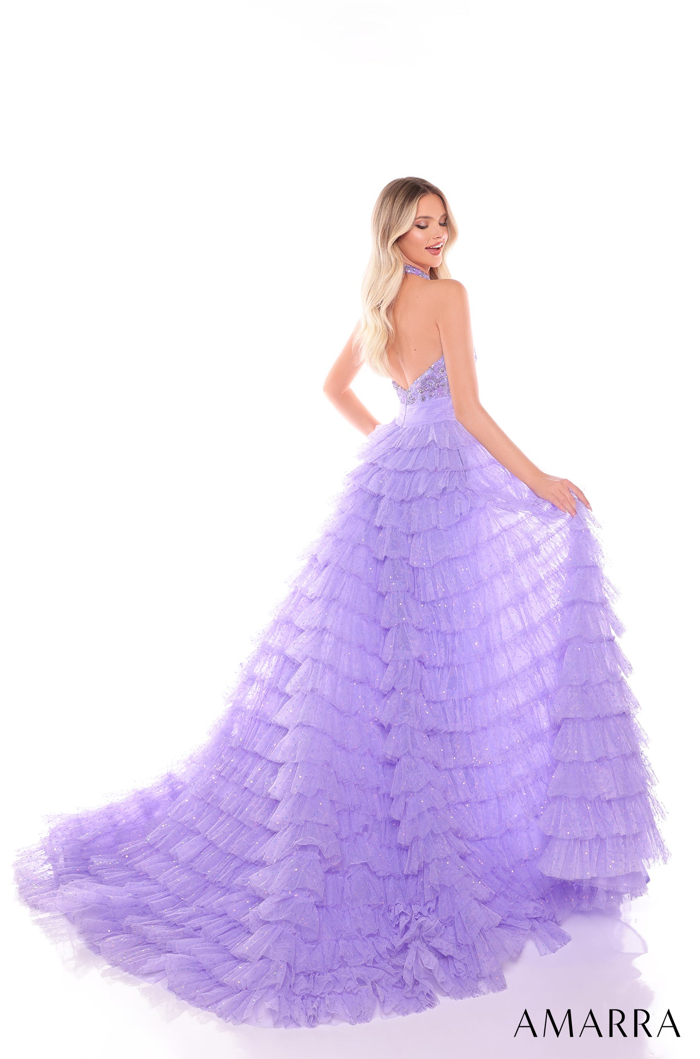 A woman wears a lavender tiered ballgown with a ruffled skirt and sparkling texture.