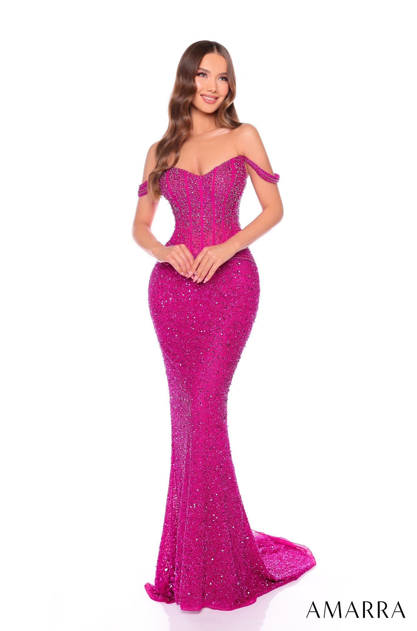 A woman wears a sparkling Bright Fuchsia off-shoulder mermaid gown with sequins and a sweeping train.