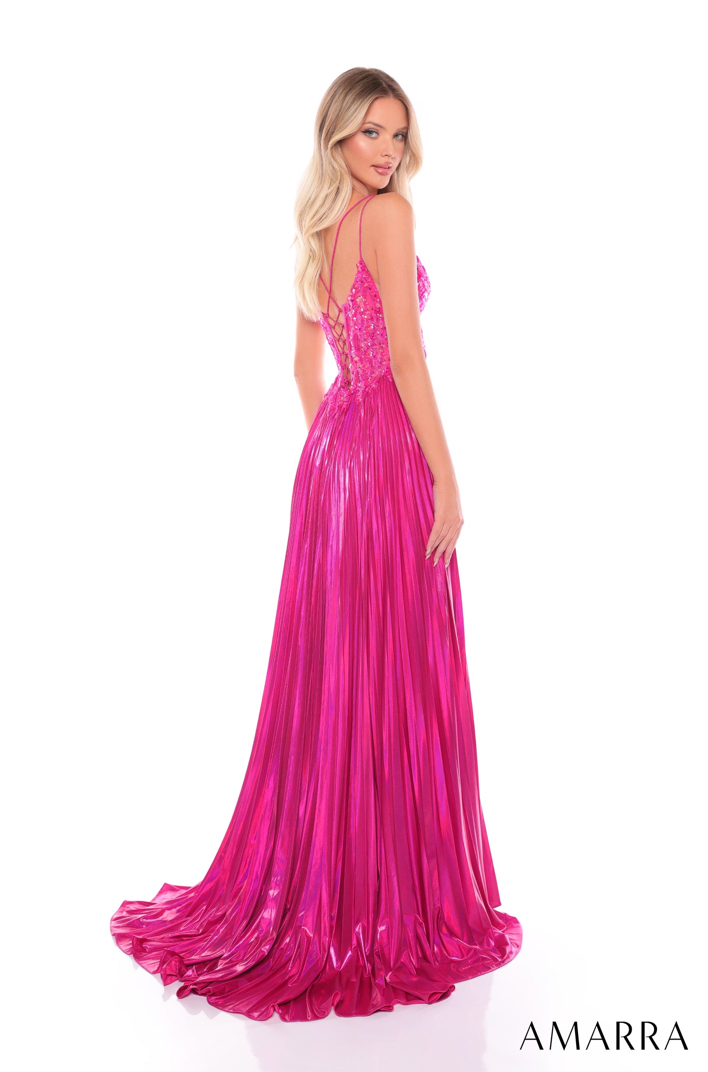 A model wears a long, hot pink sequined gown with a pleated skirt and criss-cross back straps.