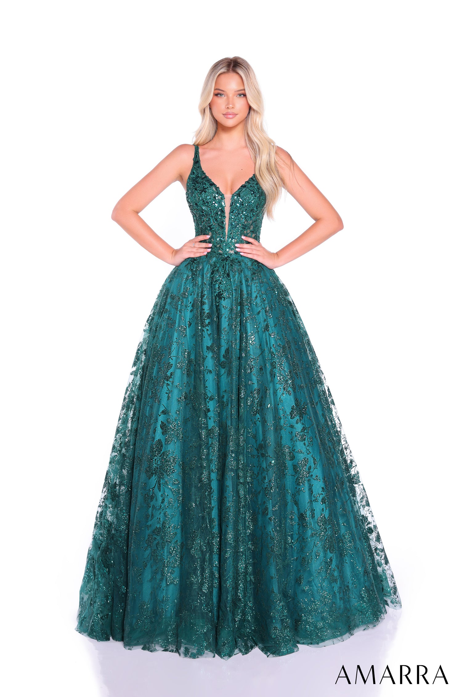 A blonde model wears a full-length emerald green sequined ball gown with a plunging neckline by Amarra.