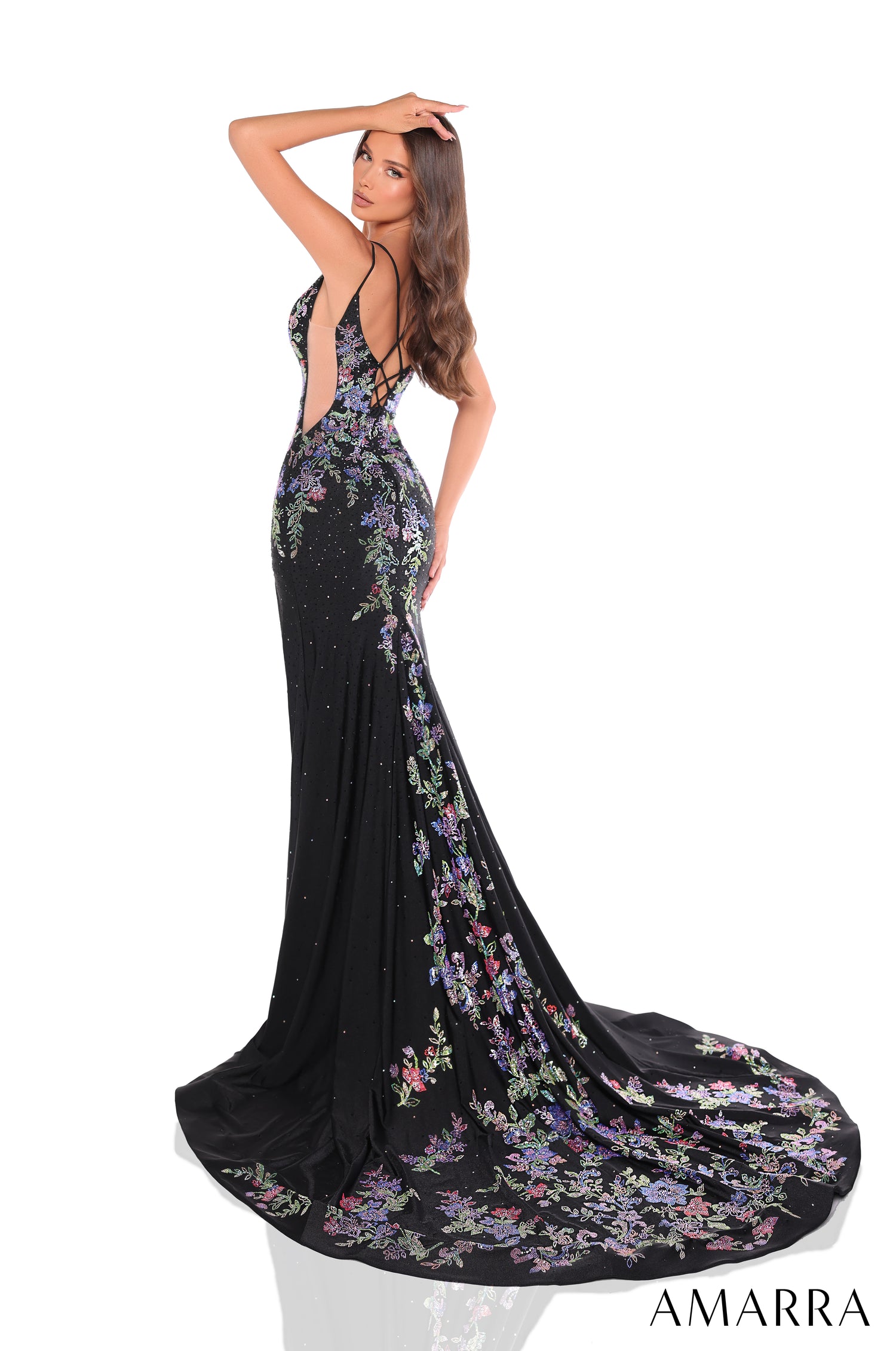 A long black gown with colorful floral embroidery and a dramatic train, worn by a woman posing elegantly.