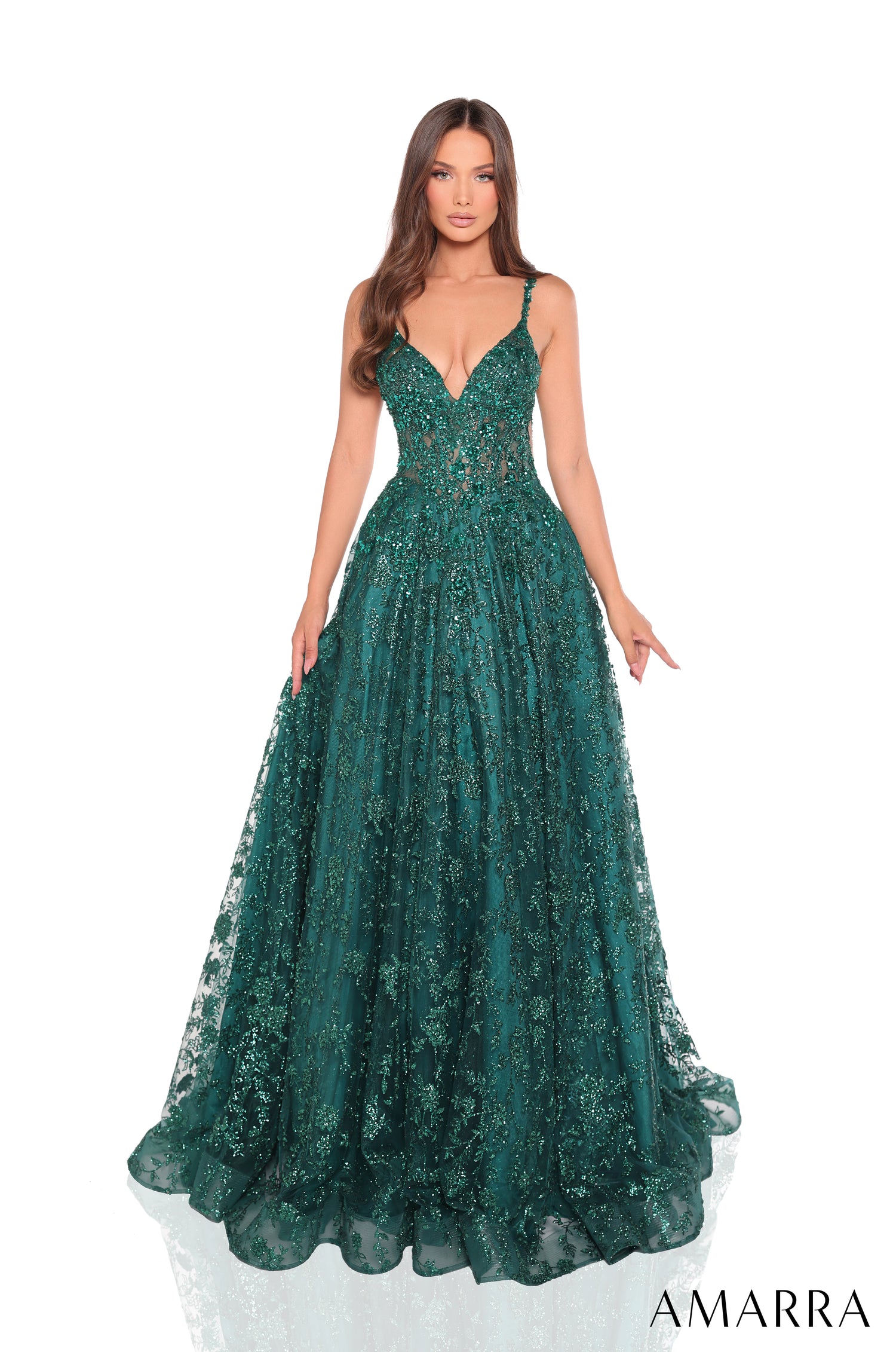 A woman wears a sparkling emerald ball gown with a plunging neckline and full, glittery tulle skirt.