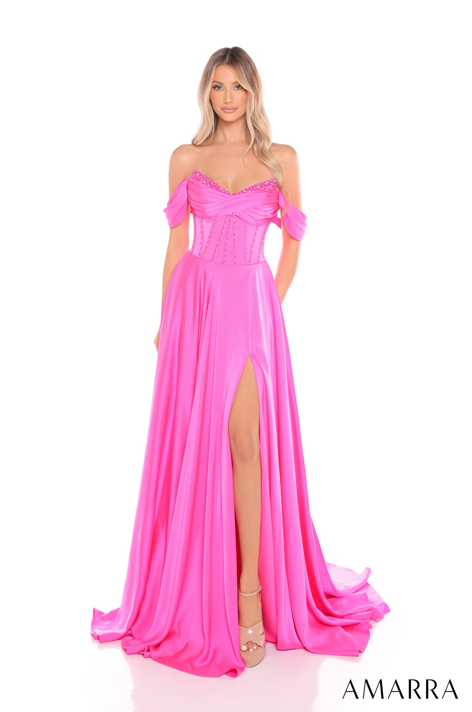 A model wears a flowing, off-shoulder Pink gown with a high slit and beaded bodice.