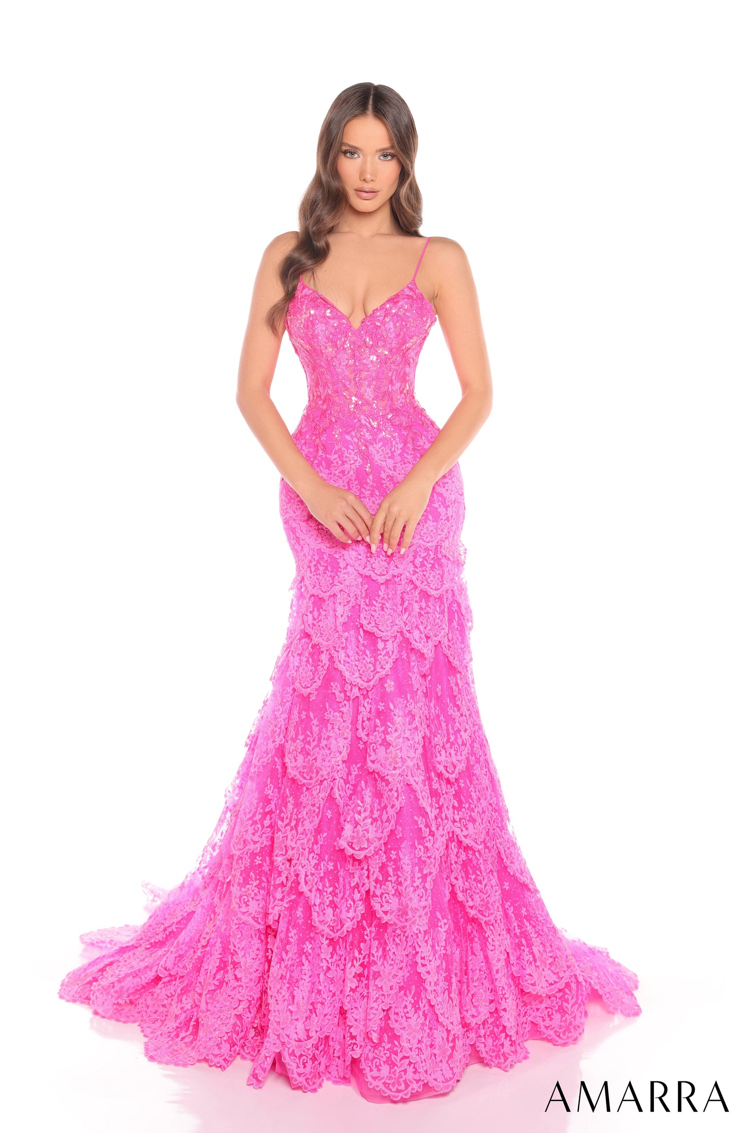 A slender model wears a fitted, long fuchsia lace mermaid gown with spaghetti straps and a flared skirt.