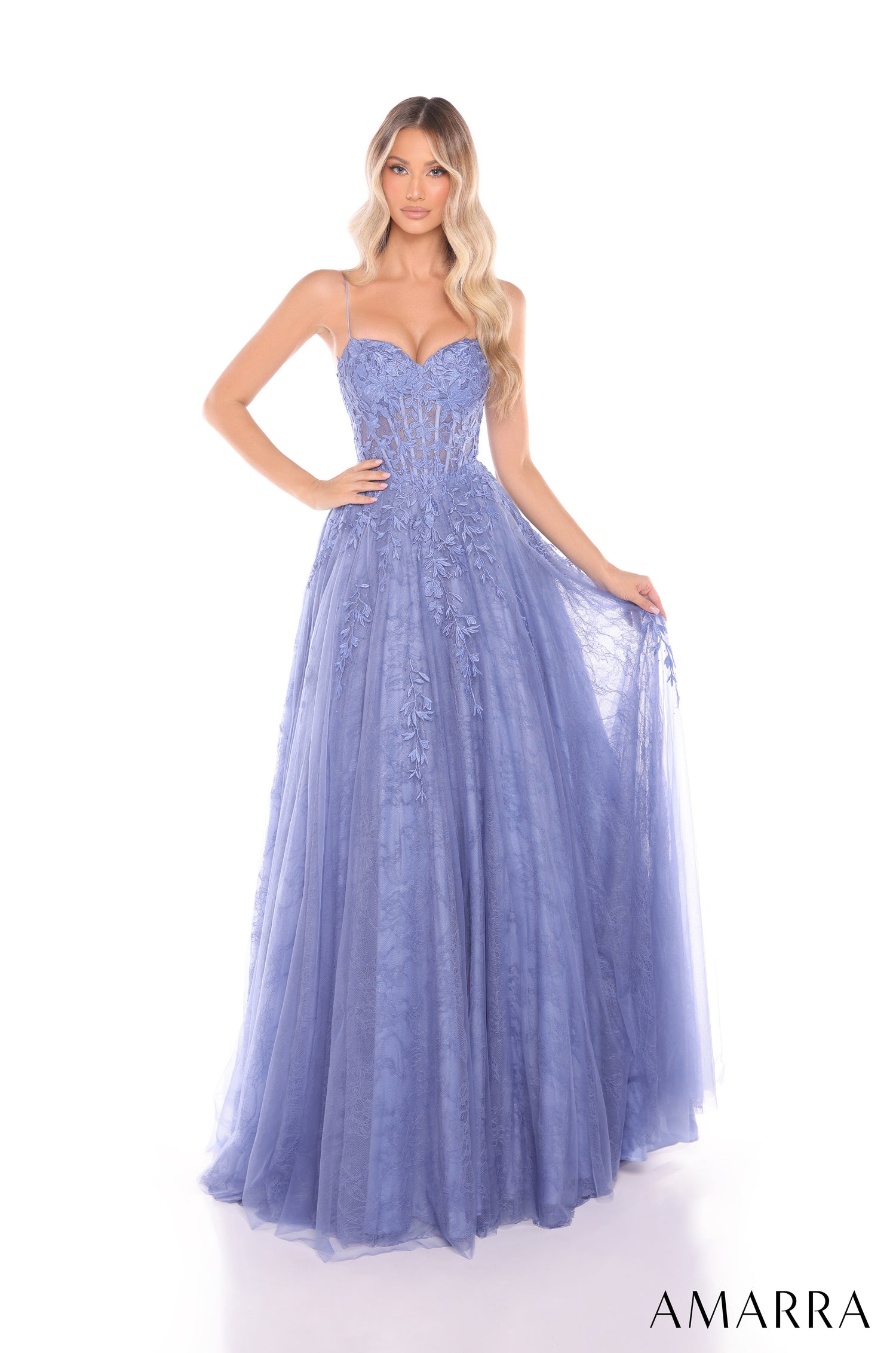A woman wears a full-length Slate Blue corset ball gown with floral embroidery and a tulle skirt.