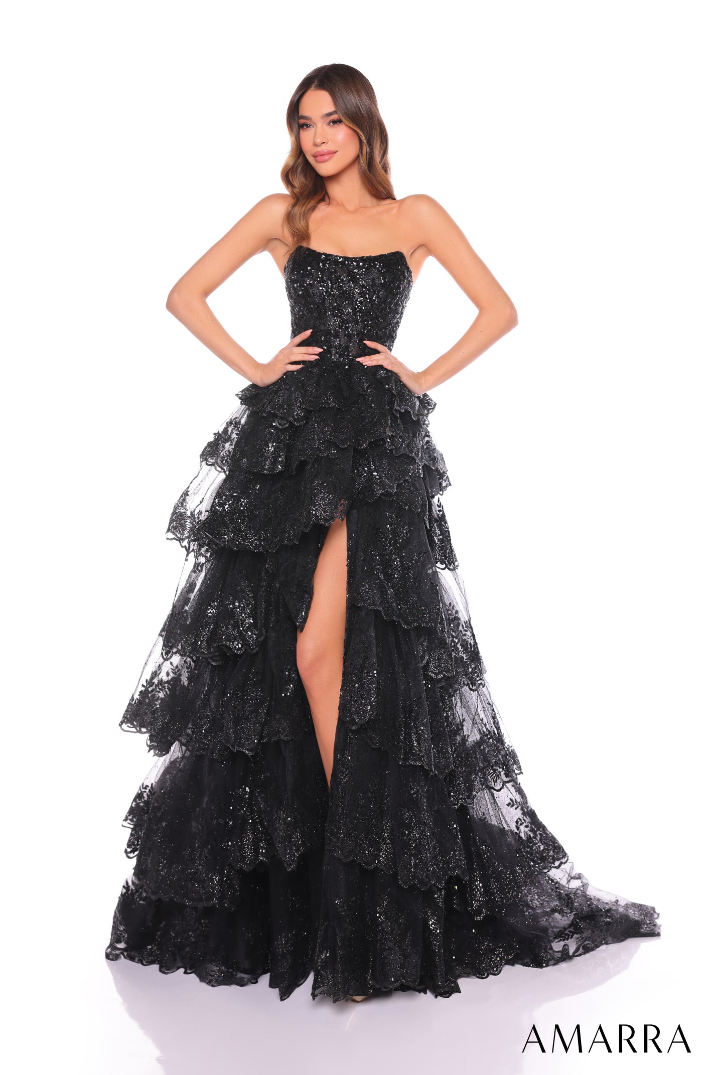 A model wears a black strapless gown with sparkling tiered lace and a high leg slit.