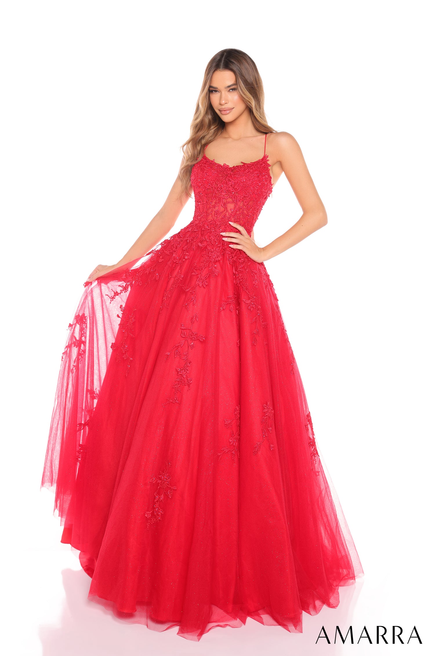 A woman wears a floor-length, lace-detailed Red ball gown with spaghetti straps and a full tulle skirt.