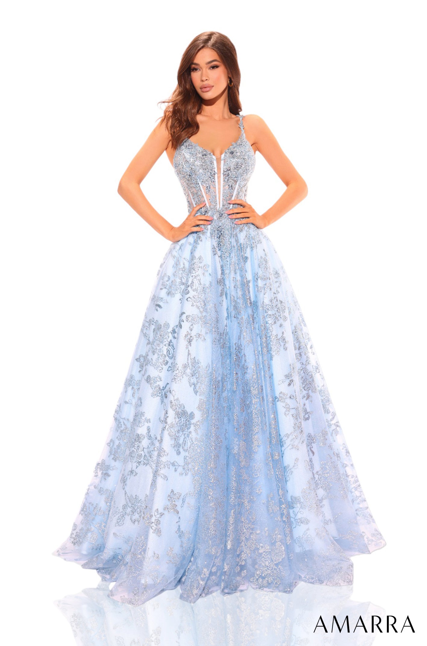 A woman wears a flowing Light Blue gown with intricate silver floral embellishments and a corseted bodice.