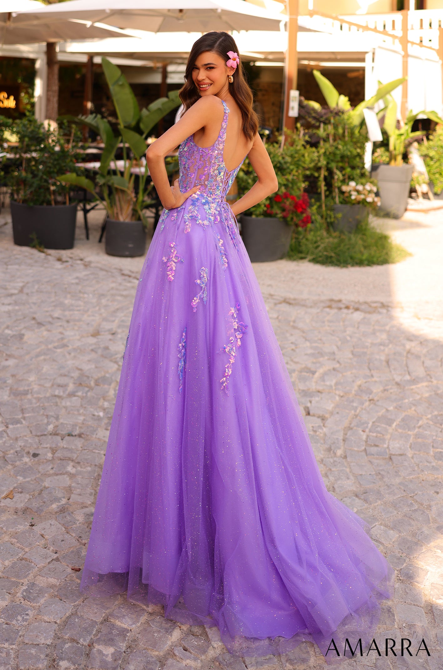 A lavender ballgown with floral embellishments and a sparkly tulle skirt, worn by a smiling model outdoors.