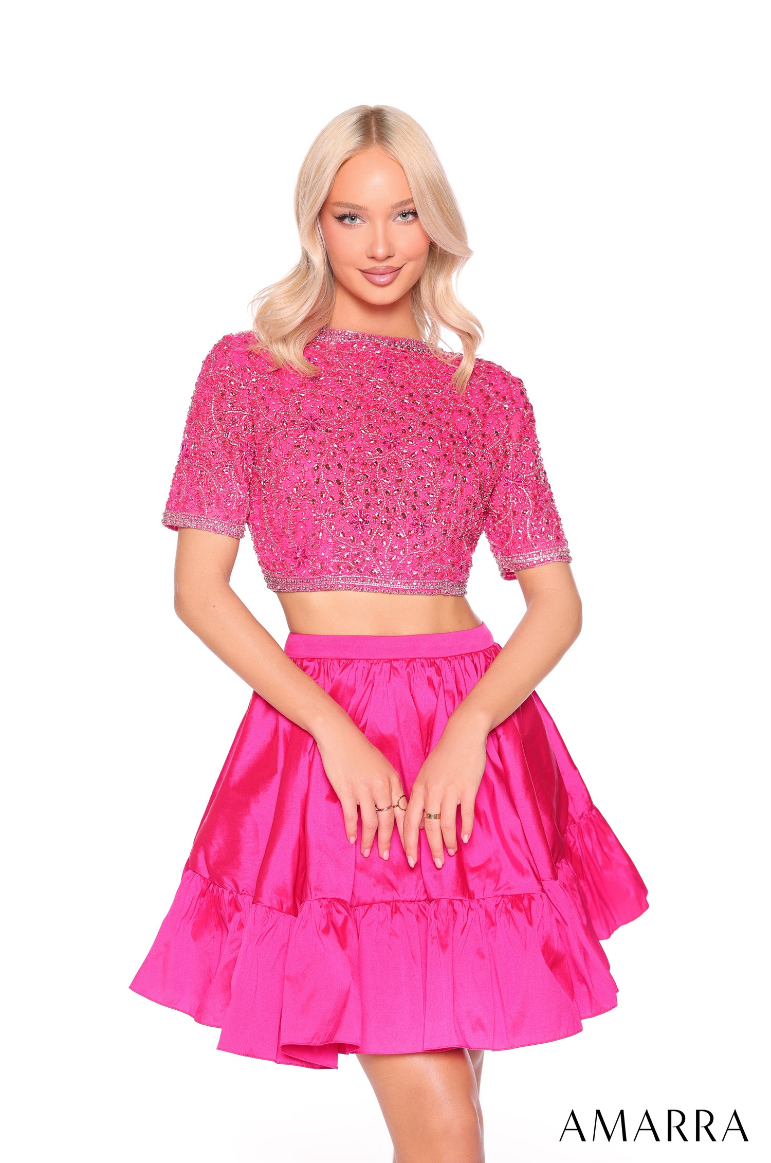 A woman wears a fuchsia two-piece dress with a beaded crop top and tiered skirt by Amarra.