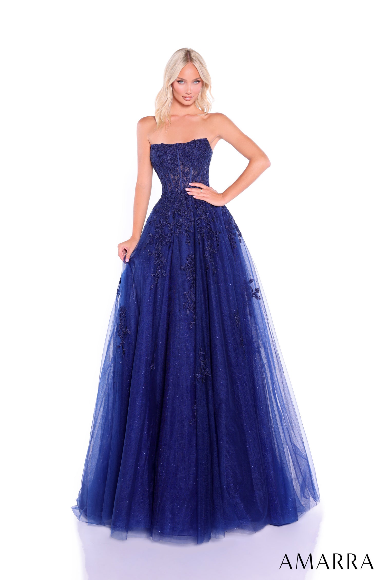 A strapless ballgown in navy tulle with intricate lace appliqués, styled on a model against a white background.