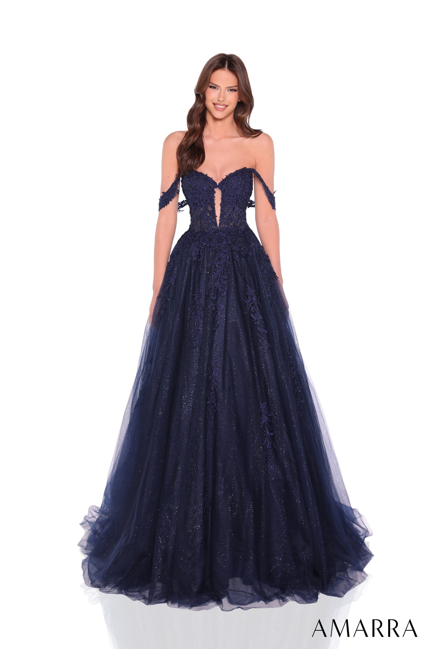 A model wears a navy strapless ball gown with a glittery tulle skirt and intricate lace bodice.