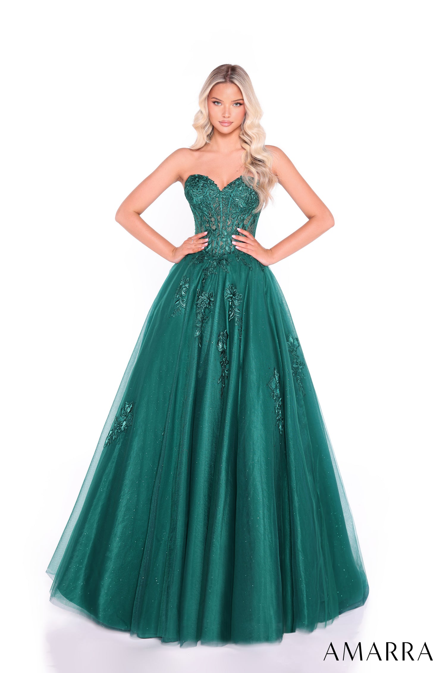 A woman wears a strapless emerald green ball gown with a corset bodice and embellished tulle skirt.