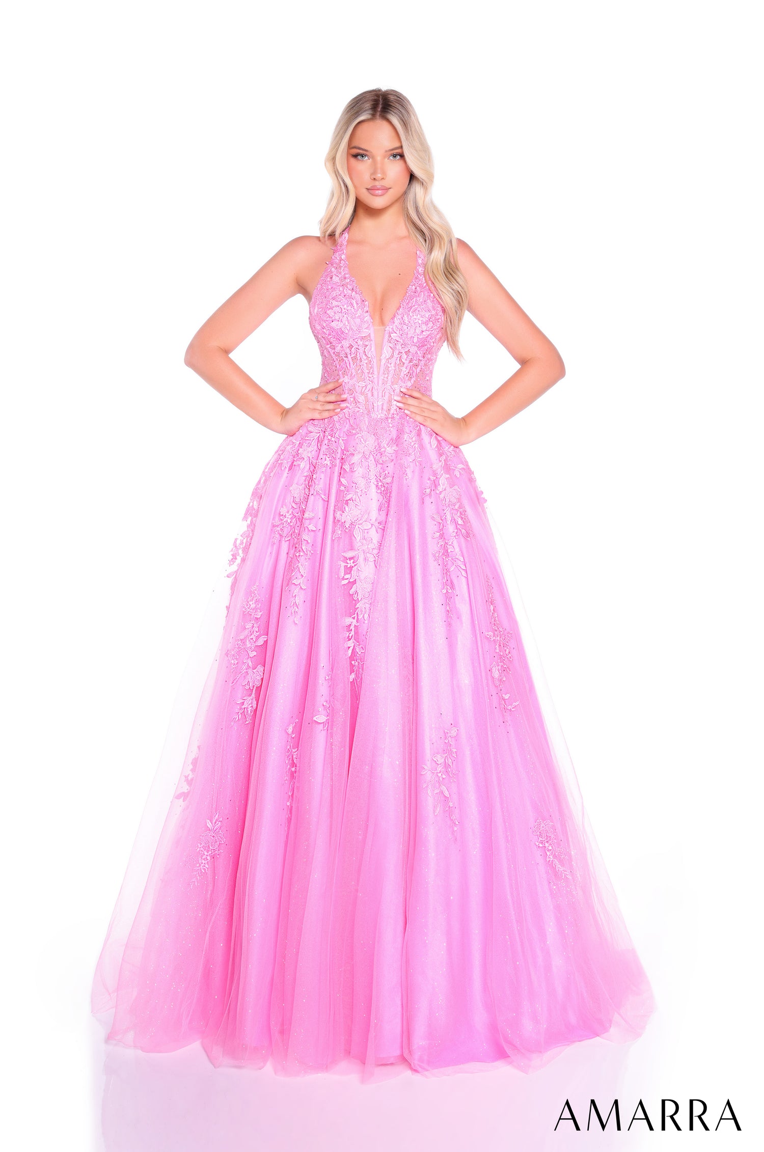 A model wears a full-length Bright Pink ball gown with lace appliqués and a plunging V-neckline.