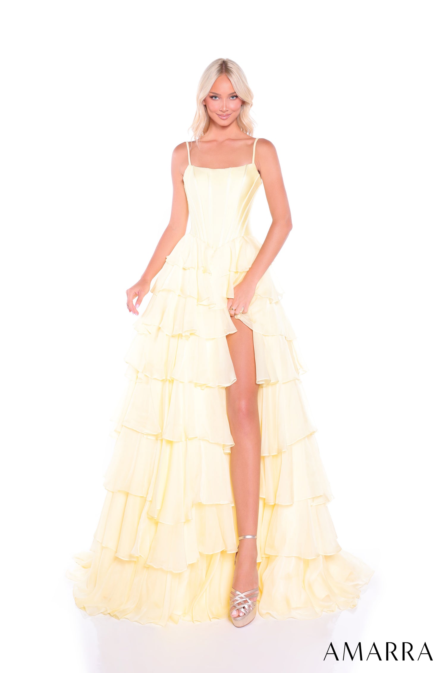 A model wears a light yellow tiered gown with spaghetti straps and a high leg slit.