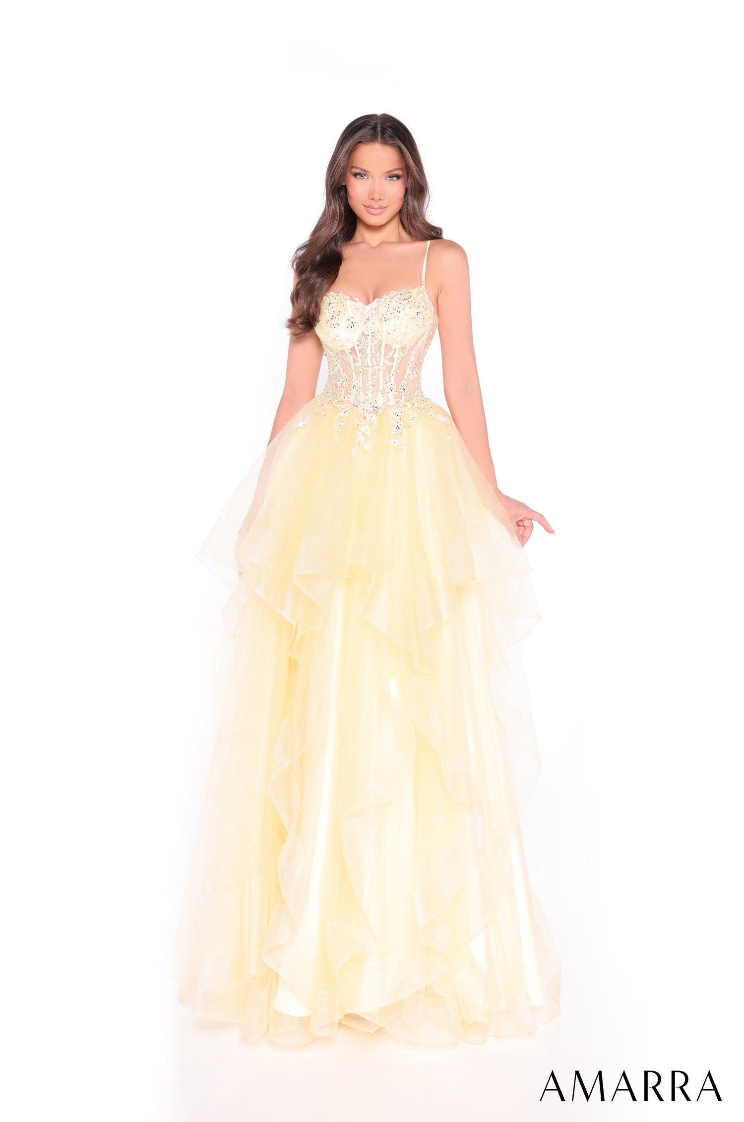 A woman wears a yellow corseted ball gown with beaded details and a flowing layered skirt.
