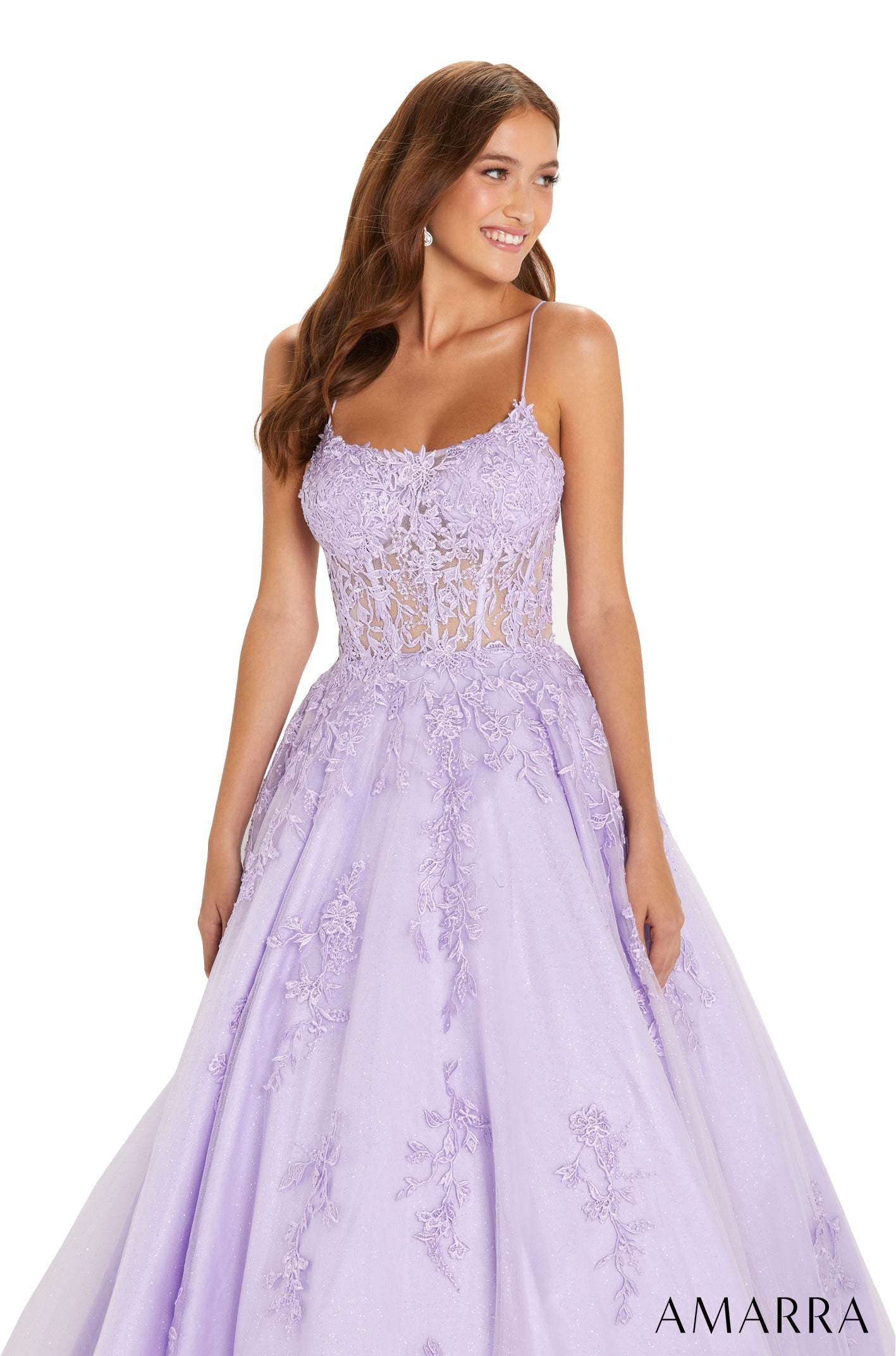 A woman wears a lavender lace ball gown with spaghetti straps and an embroidered, full skirt.
