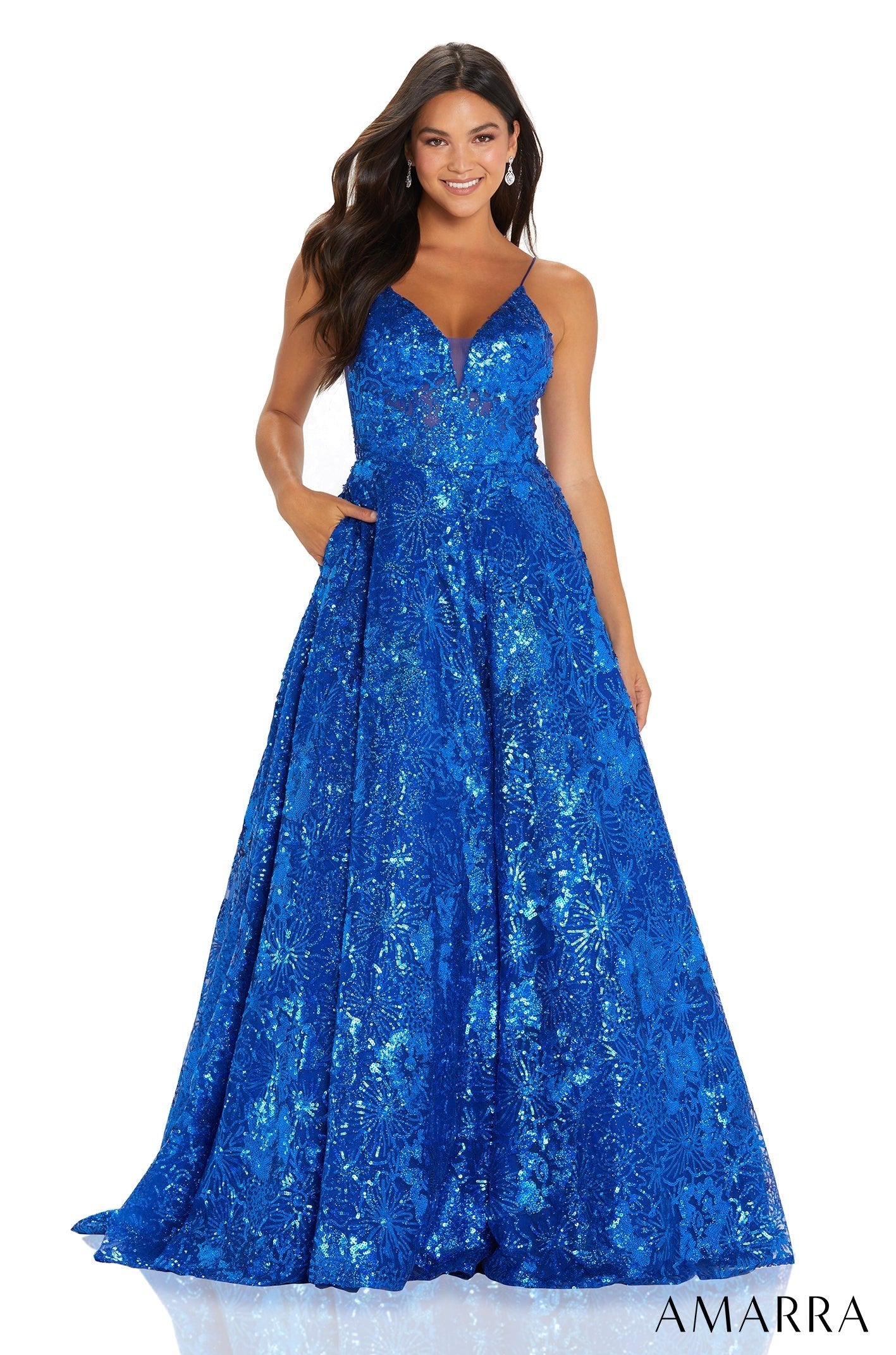 A model wears a long, royal blue sequined ballgown with a V-neck and full, sparkling skirt.