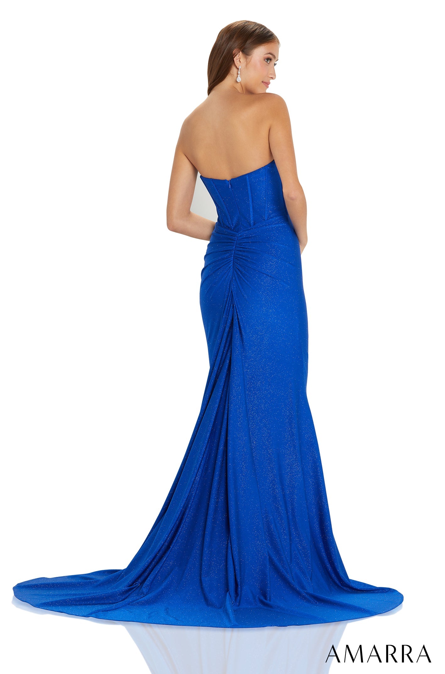 A model wears a strapless, shimmering royal blue mermaid-style gown with a long, flowing train.