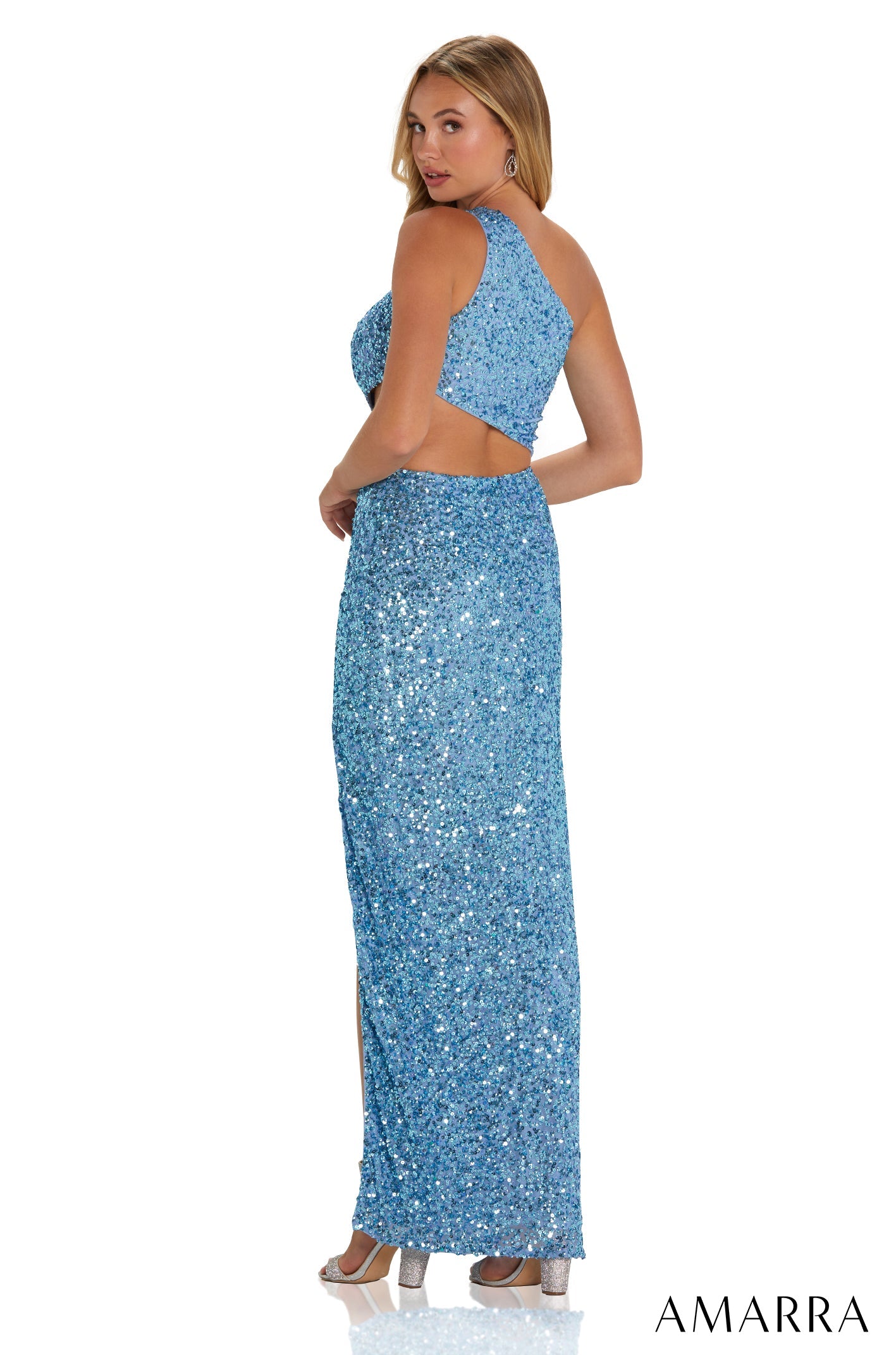 A blue sequined long evening gown with a cut-out back, styled on a model facing away in silver heels.