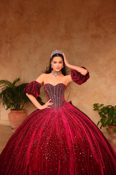 A young woman wears a sparkling deep red quinceañera ball gown with a corset top and puffy sleeves.