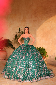 A woman wears a voluminous emerald ballgown with floral embroidery, posing against a warm-toned background.