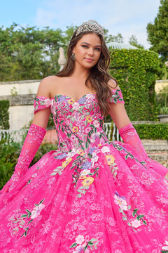 A young woman in a vibrant pink floral quinceañera gown wears a tiara and long gloves in a garden setting.