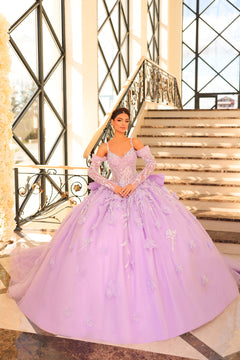 A woman wears a voluminous dusty lilac ball gown with lace details, standing on an elegant staircase.