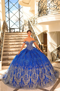 A woman in a royal blue off-shoulder ball gown stands on an ornate staircase with intricate metalwork.