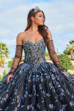 A young woman wears a glittering dark blue quinceañera gown with sheer sleeves and an ornate tiara.