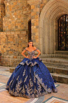 A woman in a navy ball gown with gold lace details stands confidently before a stone archway and ornate door.