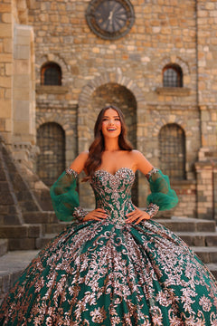 A woman in an emerald green and silver quinceañera gown poses dramatically in front of a stone castle.