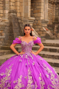 A woman wears a vibrant purple ball gown with floral embellishments, standing on stone steps.