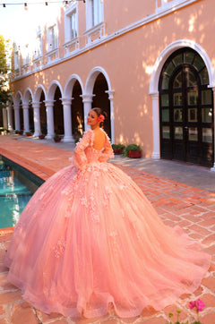 A woman in a voluminous pink ball gown poses beside a colonnade with a swimming pool.