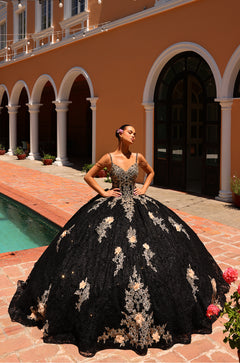A woman in a black and gold ballgown poses by a pool at a Mediterranean-style venue with arched columns.