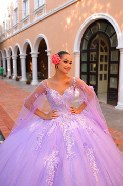 A woman in a lavender ball gown with floral accents poses in front of an arched building with white columns.