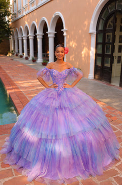 A young woman wears a voluminous Lilac/Multi quinceañera ball gown with puffy sleeves and a jeweled bodice.