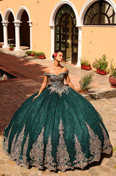 A woman wears a sparkling emerald/gold off-shoulder quinceañera ball gown with intricate lace details in an arched.